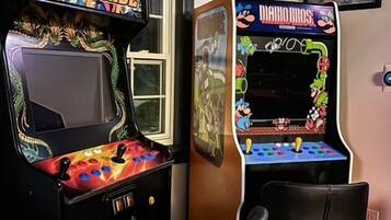 Two arcade machines, a window with a view, and a framed picture on the wall.