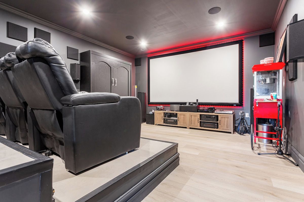 Ein Heimkinozimmer mit einer großen Leinwand, einem Liegesessel und einem roten Wagen mit Audioausrüstung.