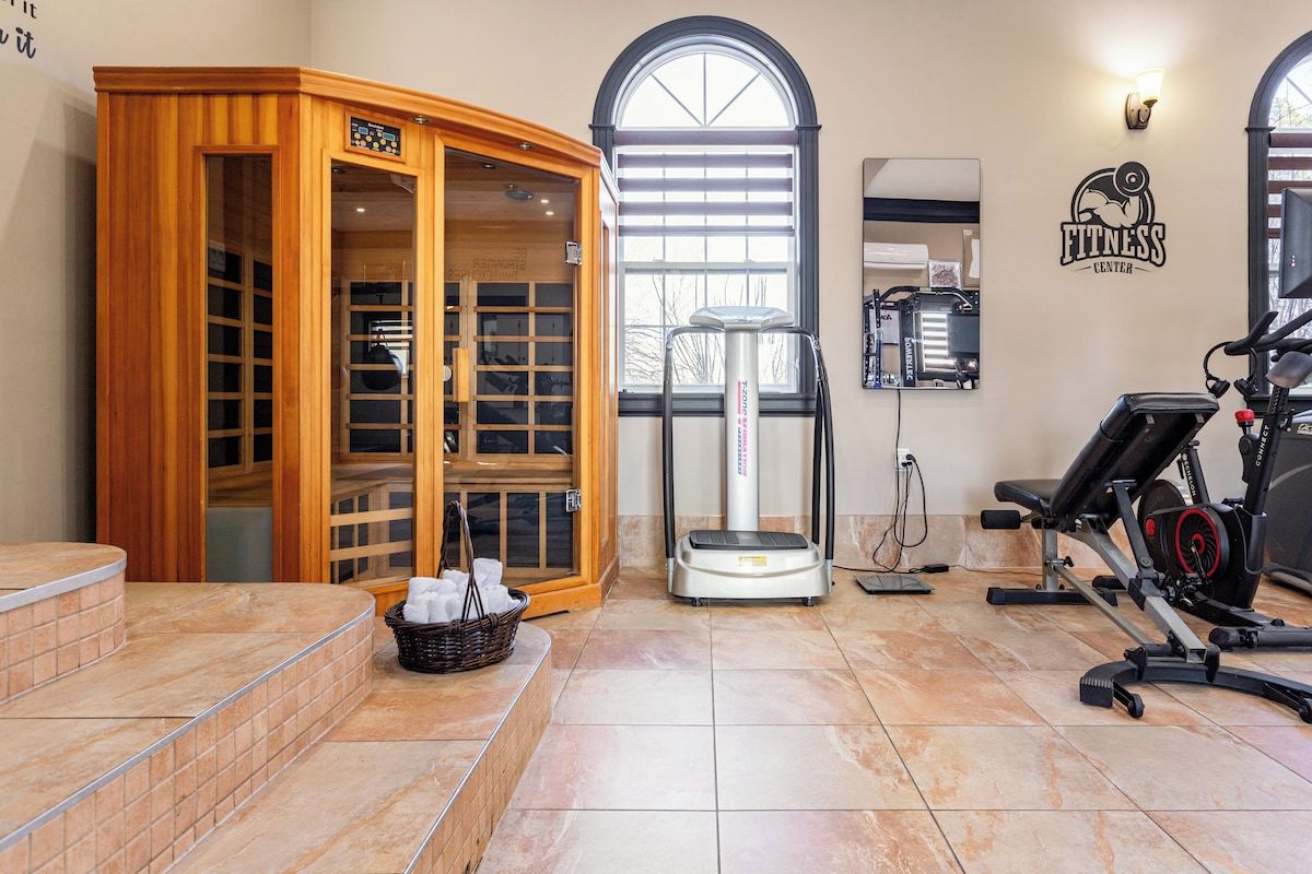 Ein Fitnessstudio mit Sauna, Trainingsgeräten und einem großen Fenster.