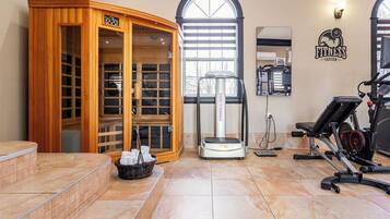 Ein Fitnessstudio mit Sauna, Trainingsgeräten und einem großen Fenster.