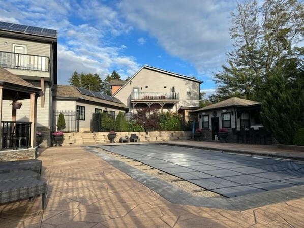 A residential area with a swimming pool, a two-story house, and a patio.