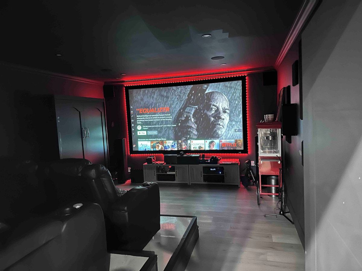 Un cine en casa con una pantalla grande, asientos cómodos y un sistema de sonido.