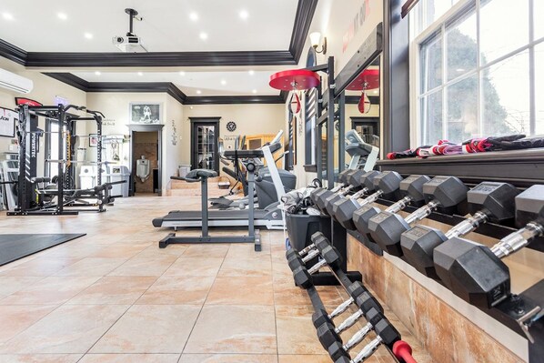 A gym with various exercise equipment, including treadmills, weight machines, and a rack of dumbbells.