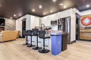 A modern kitchen with a microwave, refrigerator, and a dartboard on the wall.