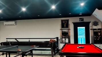 Una sala de billar con mesa de billar, mesa de snooker y dardos.