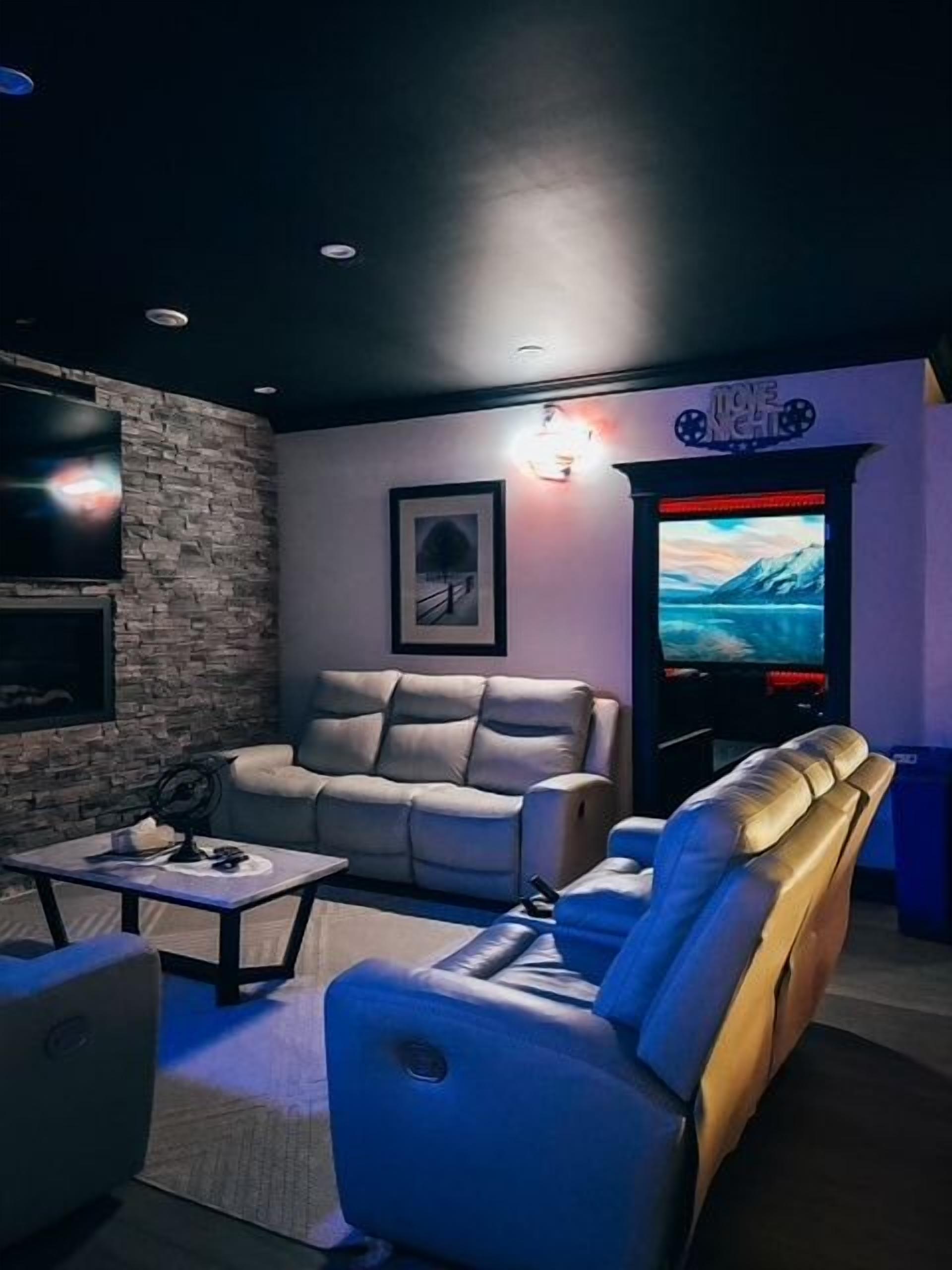 Una habitación con un sofá, un sillón reclinable, un televisor de pantalla plana y un televisor instalado en la pared.