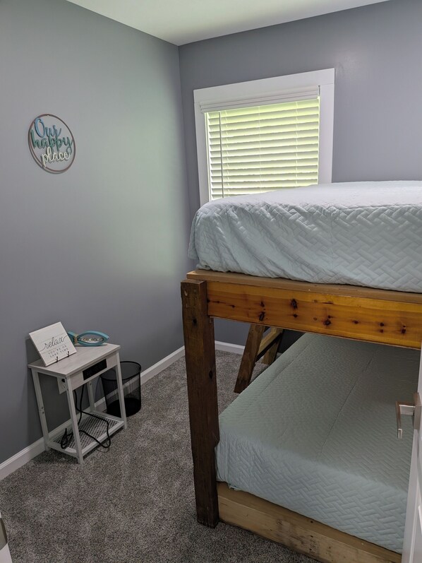 A bedroom with a bunk bed, a small desk with a sign, a window with blinds, and a wall decoration. - Brand New Floating Home on Norris Lake : Sleeps 12 : Swim, Grill & Relax! #3 (LaFollette)