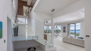 Een modern interieur met een trap, een eethoek en uitzicht op het buitenleven.