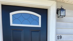 A dark blue door with a decorative glass panel, a keypad lock, and a number '19' on the adjacent wall.