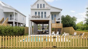A two-story house with a covered patio, a pool, and a wooden fence.