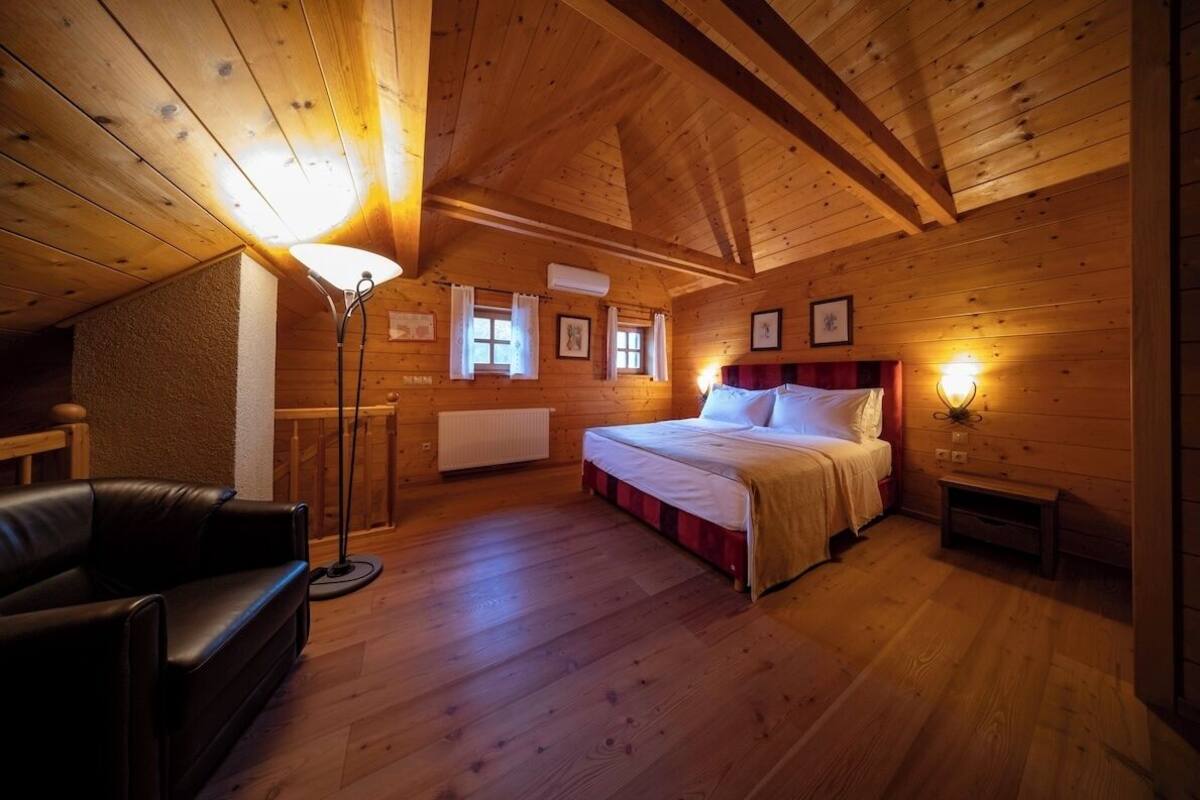 A cozy wooden cabin bedroom with a bed, a desk, and a chair.