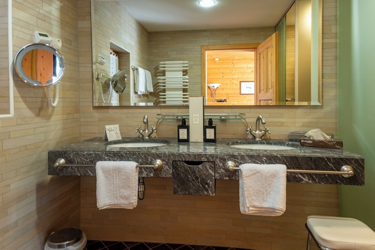 A modern bathroom with two sinks, a mirror, and a vanity.