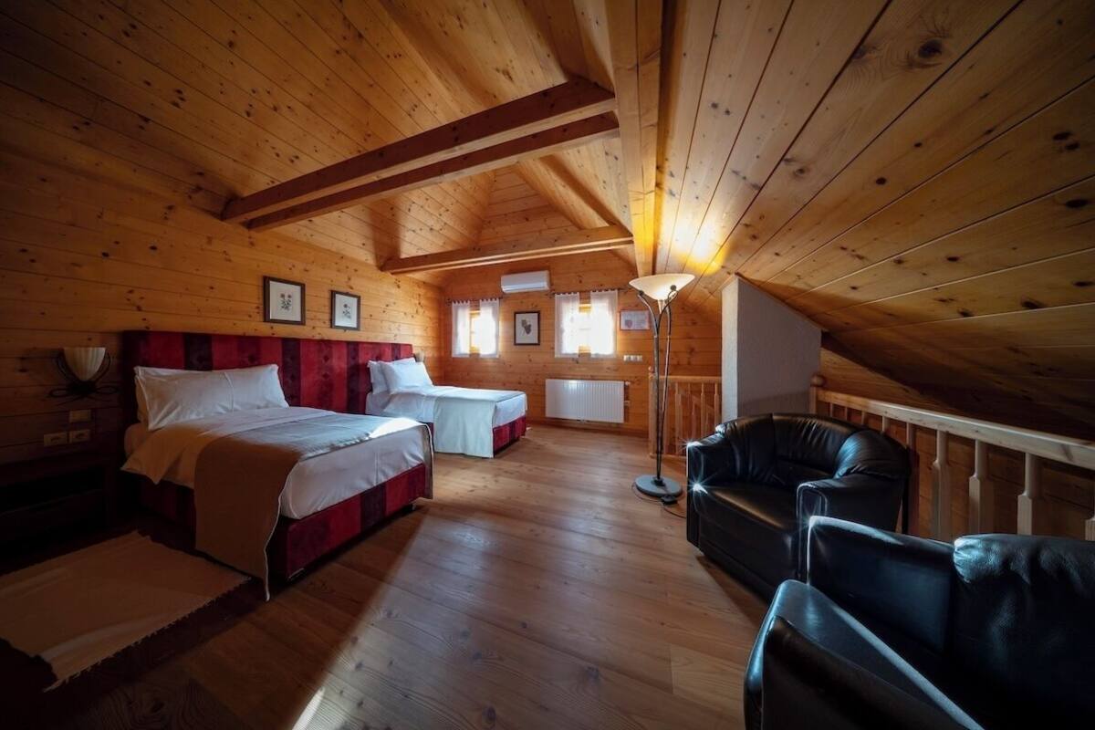 A cozy cabin with two beds, a sofa, and a lamp.