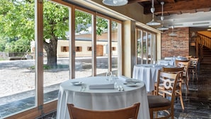 A restaurant with round tables, large windows, and a brick wall. - Posestvo Pule Equestrian Estate (Mokronog-Trebelno)