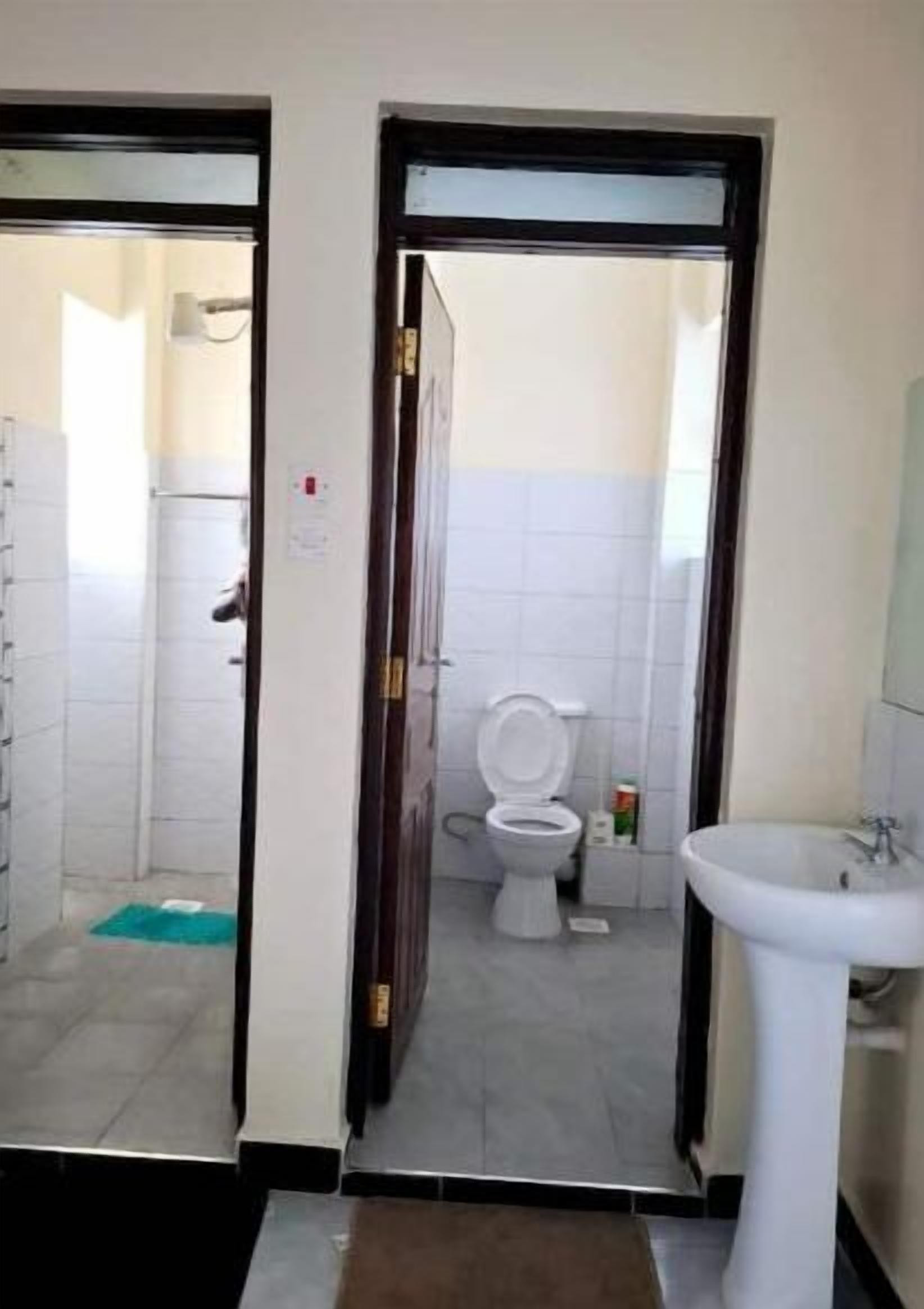 Un baño con inodoro, lavamanos y zona de ducha.