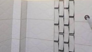 A bathroom with a shower, a white ceiling, and a tiled wall with a geometric pattern. - Elegant Studio (Kiambu)