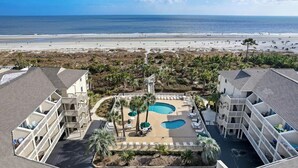 Un complexe hôtelier doté d’une piscine, offrant une vue sur la plage et comprenant plusieurs bâtiments.