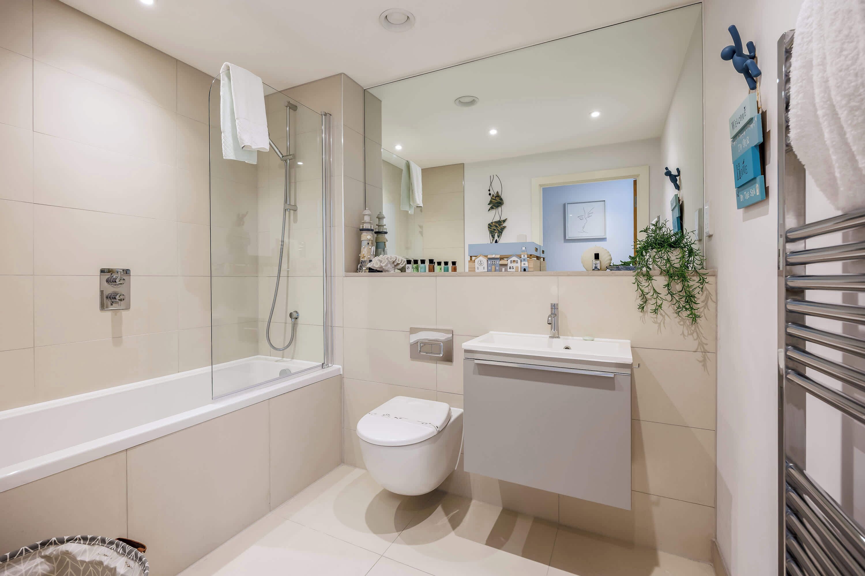 A modern bathroom with a glass-enclosed shower, a white toilet, and a sink with a mirror above it.