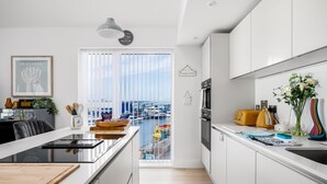 Une cuisine moderne dotée d’un grand îlot central, offrant une vue sur un port de plaisance, et un coin repas avec vue.