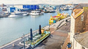 Un port de plaisance avec des bateaux amarrés, un espace de repos abrité et un bâtiment avec une enseigne bleue.