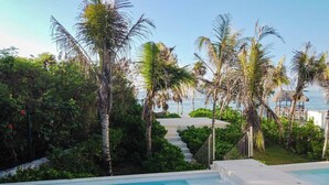 A swimming pool surrounded by palm trees and a view of the ocean. - Akumal Seaside Ocean View | Beach Access 11 Pools (Akumal)