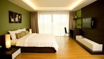 A modern hotel room with a large bed, a desk with a chair, a flat-screen TV, and artwork on the walls.