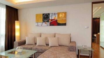 A modern living room with a sofa, a glass coffee table, and a painting on the wall.