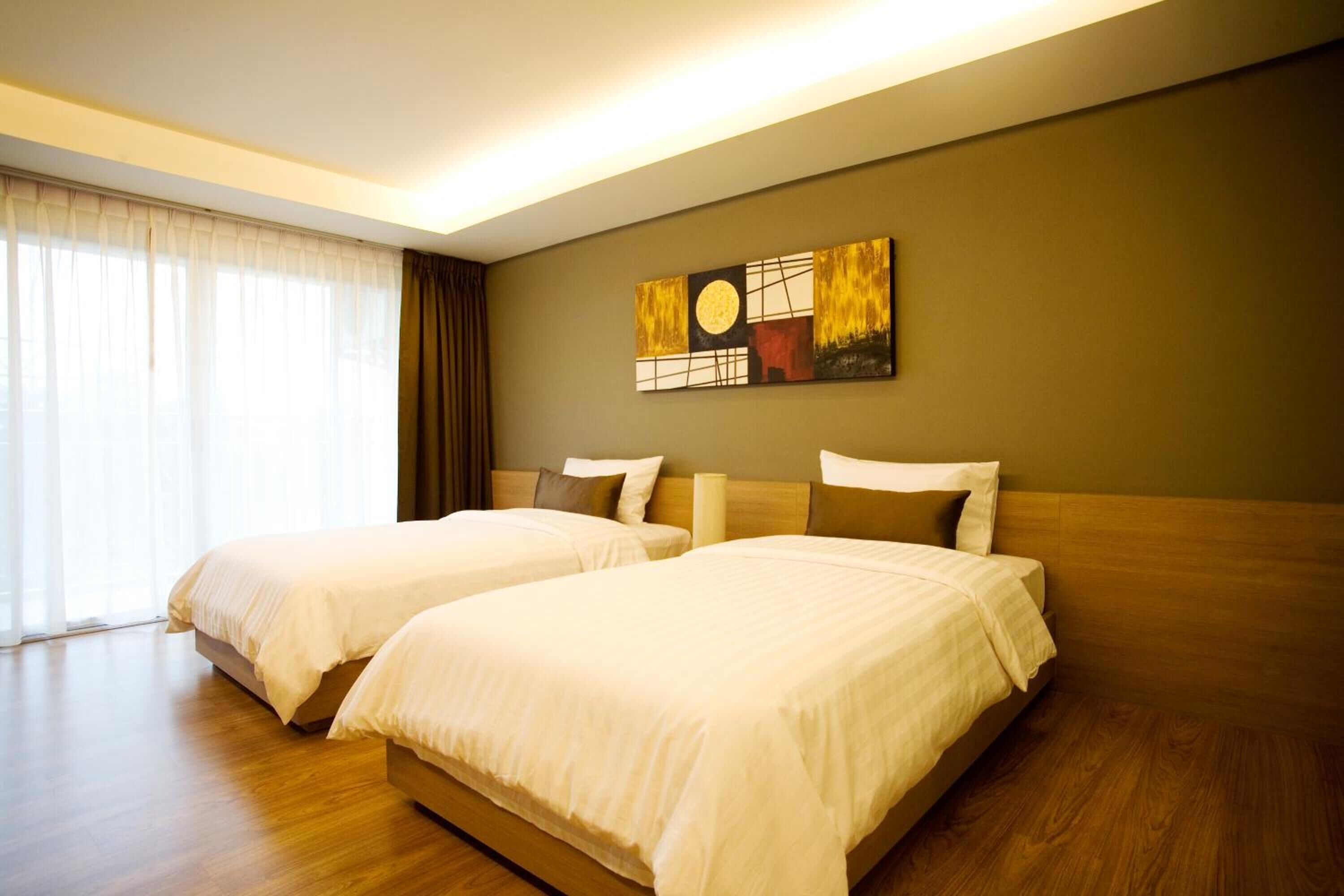 A hotel room with two beds, a large window with curtains, and a painting on the wall.