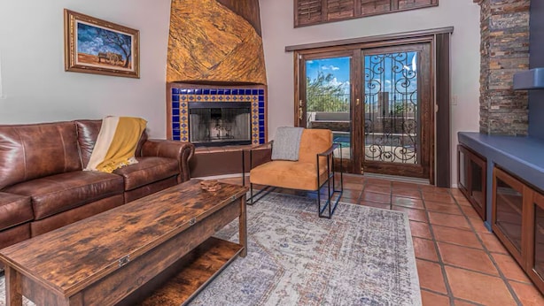 A living room with a brown leather sofa, a wooden coffee table, a blue-tiled fireplace, and a stone fireplace.