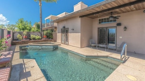 A pool area with a clear pool, lounge chairs, and a palm tree.