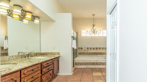 A bathroom with a large mirror, double sink vanity, and a shower area.