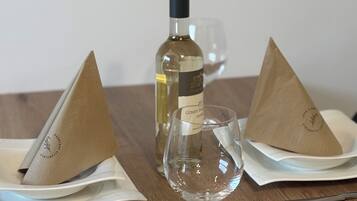 Una mesa con una botella de vino, dos servilletas dobladas, una copa de vino y cubiertos.