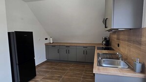 A compact kitchen with grey cabinets, a wooden countertop, a stainless steel sink, and a black refrigerator. - Quiet time out in Soltau (Soltau)