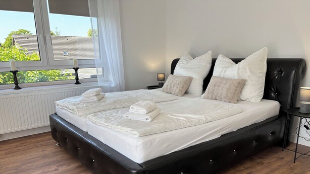 A modern bedroom with a large bed, white linens, and a fluffy rug. - Quiet time out in Soltau (Soltau)