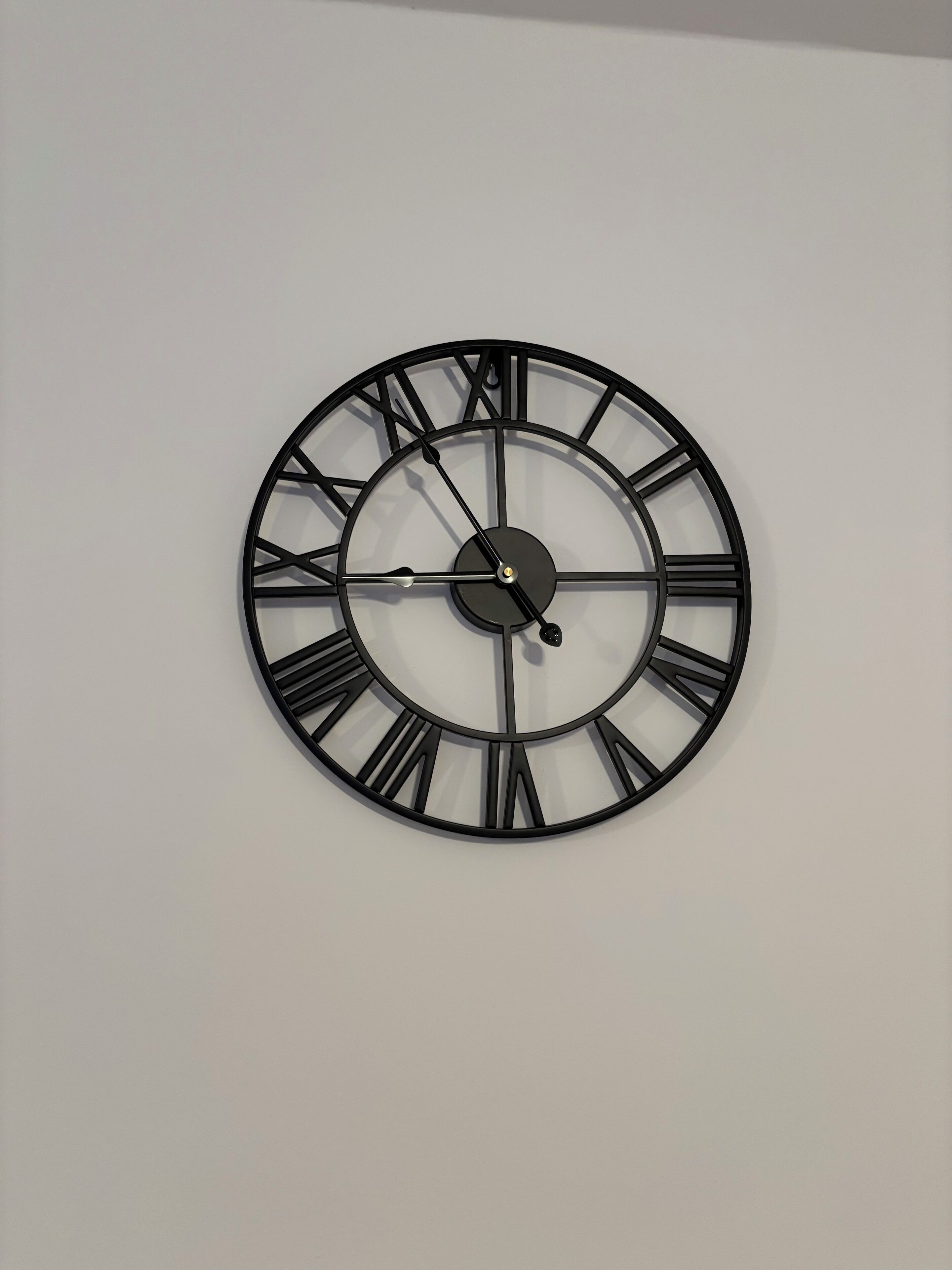 Eine wandmontierte Uhr mit römischen Ziffern und schlichtem Design.