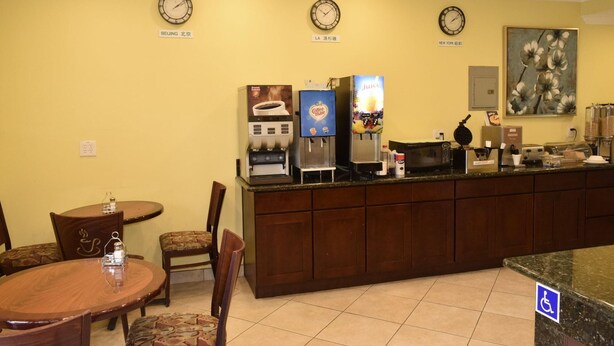 A hotel lobby with a reception desk, clocks displaying Beijing, LA, and New York times, a coffee machine, and a painting on the wall. - Garden Inn San Gabriel (Temple City)