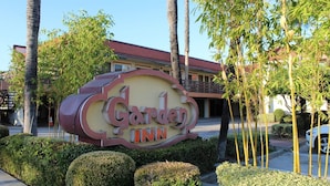 A sign for Garden Inn with a building in the background. - Garden Inn San Gabriel (Temple City)