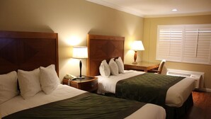 Ein Hotelzimmer mit zwei Betten, Nachttischlampen, einem Nachttisch, einem Schreibtisch und einem Fenster mit Jalousien.
