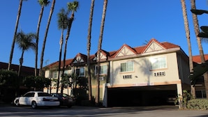 A multi-story building with a red-tiled roof, multiple windows, and a garage entrance. - Garden Inn San Gabriel (Temple City)