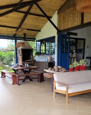 An outdoor patio with a brick oven, wooden furniture, and potted plants. - La María Nature Reserve – Infinity Pool, Mountain Views, and Horses (Armenia)