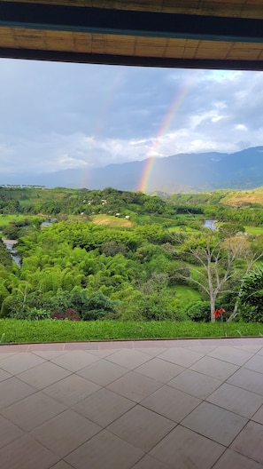 A view of a lush green landscape with a rainbow, a river, and distant mountains.