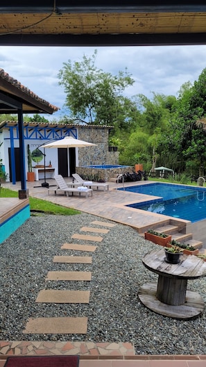 A pool area with lounge chairs, a stone wall, and a covered seating area. - La María Nature Reserve – Infinity Pool, Mountain Views, and Horses (Armenia)