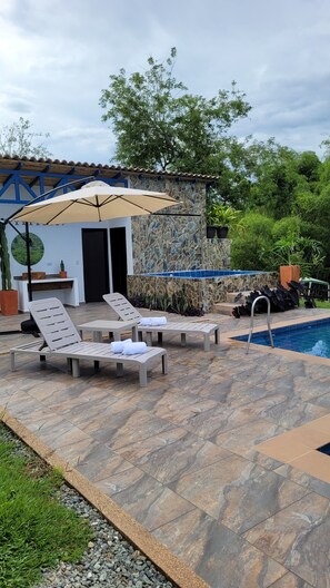 A poolside area with lounge chairs, a stone wall, and a tiled floor. - La María Nature Reserve – Infinity Pool, Mountain Views, and Horses (Armenia)
