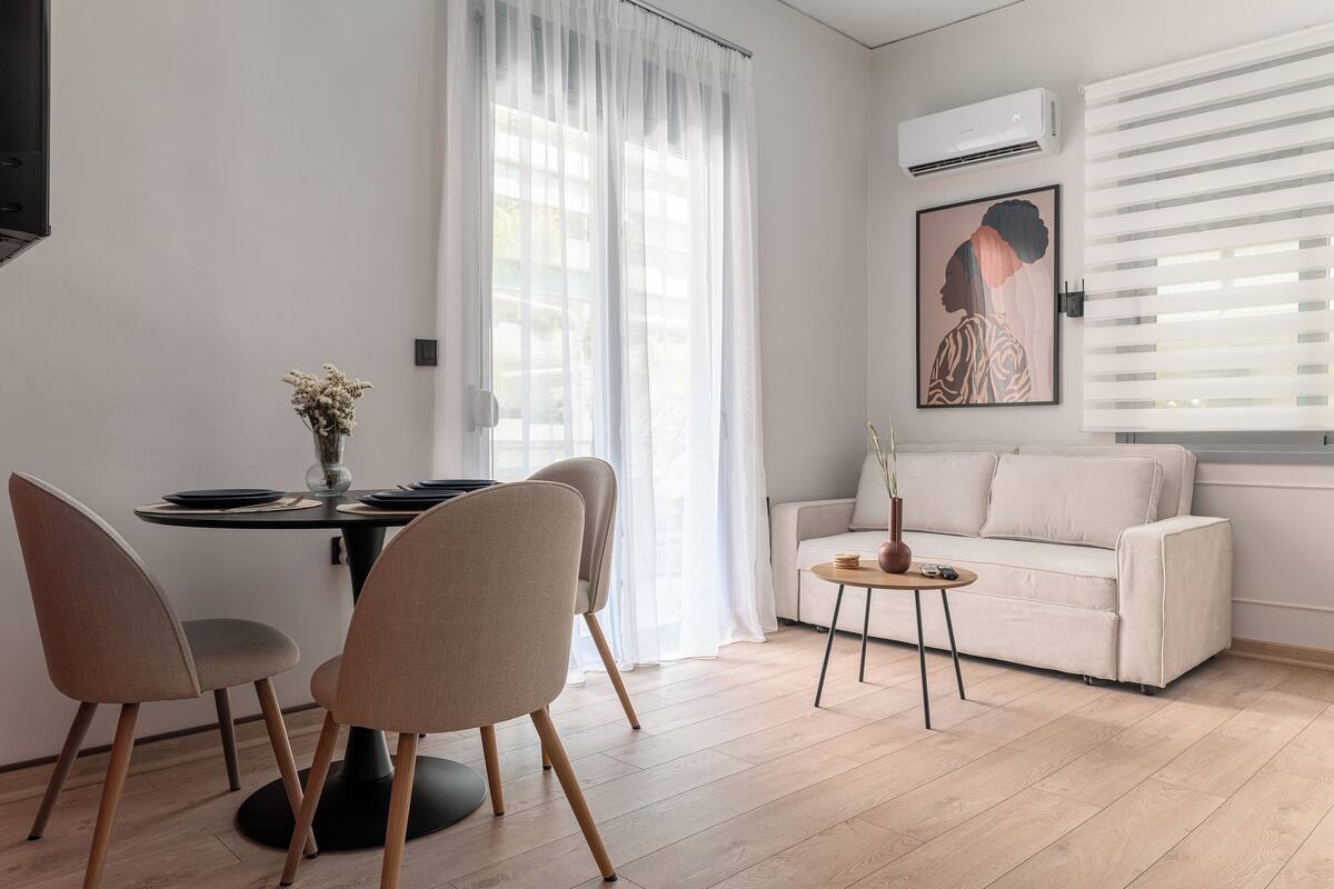 A modern living room with a dining area, featuring a sofa, a dining table with chairs, and a small side table.