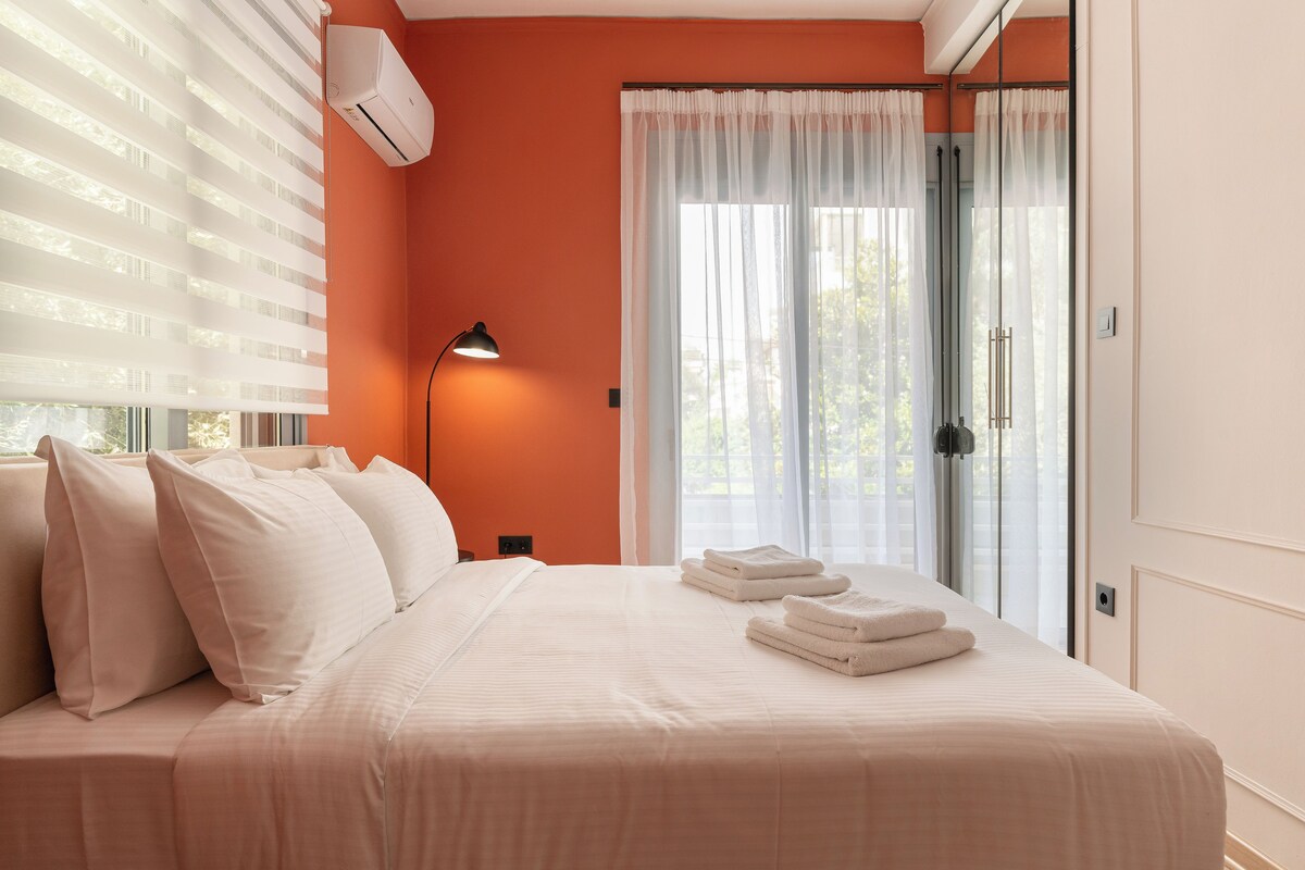 Un letto rifatto con cuscini, una lampada da comodino e asciugamani piegati.