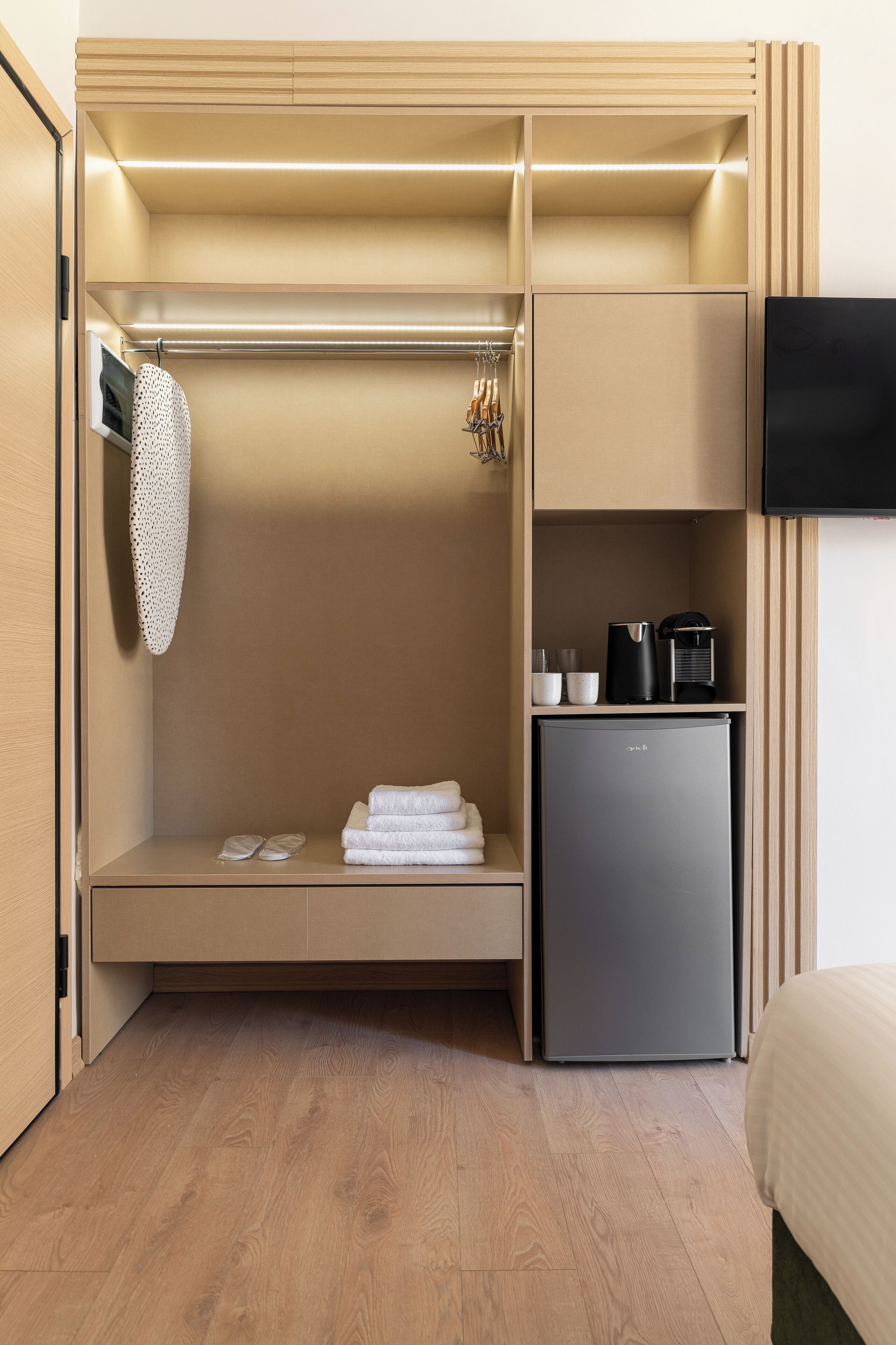Ein kompaktes Zimmer mit integriertem Kleiderschrank, einer kleinen Küchenzeile und einem wandmontierten Flachbildfernseher.