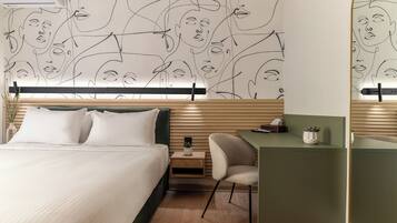 A modern hotel room with a bed, a desk, and a wall with abstract line art.