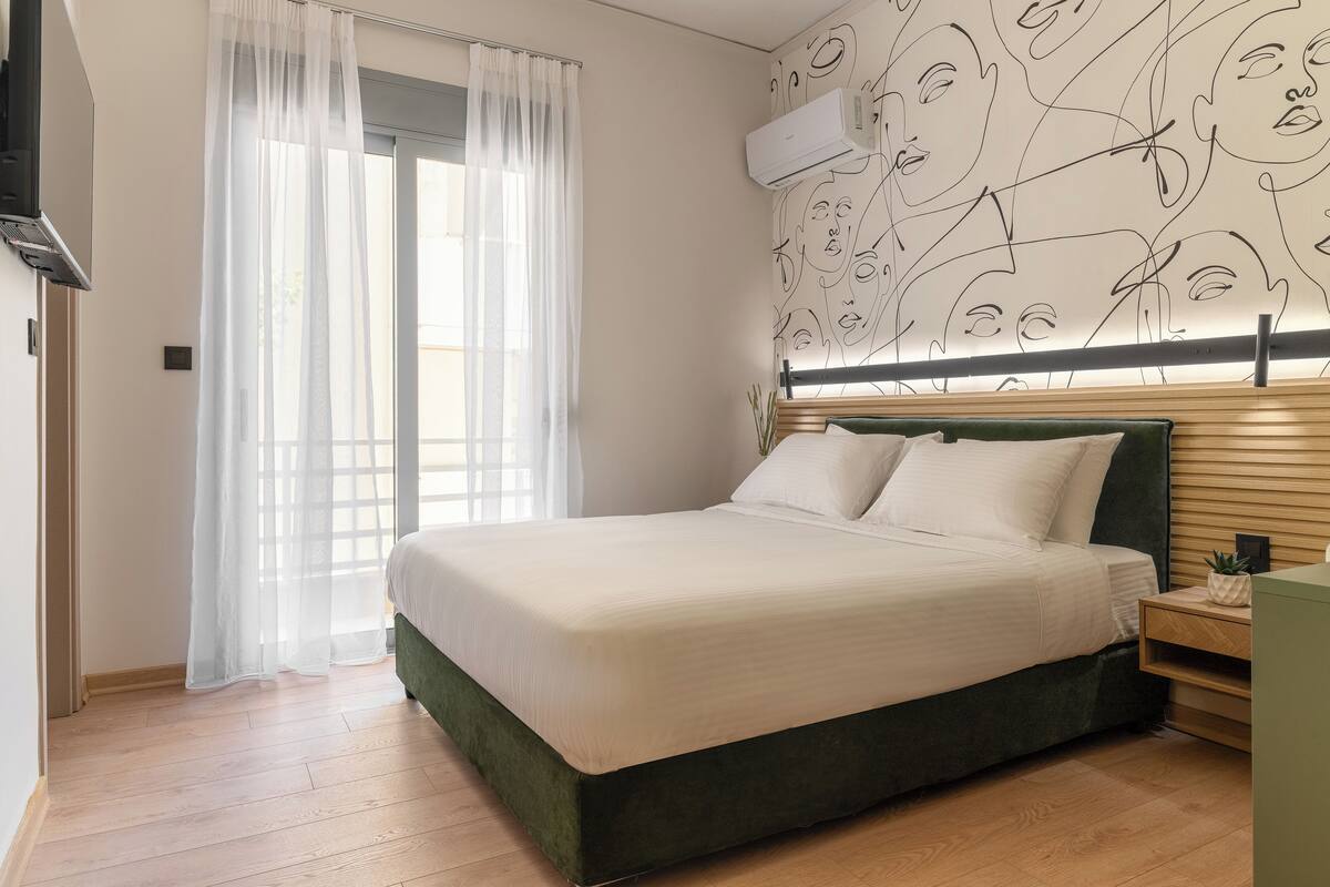 A bedroom with a bed, a nightstand, a potted plant, and a wall with a face pattern.