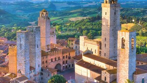 A historic town with prominent medieval towers and a central building with arched windows. - La Casa di Ines (San Gimignano)