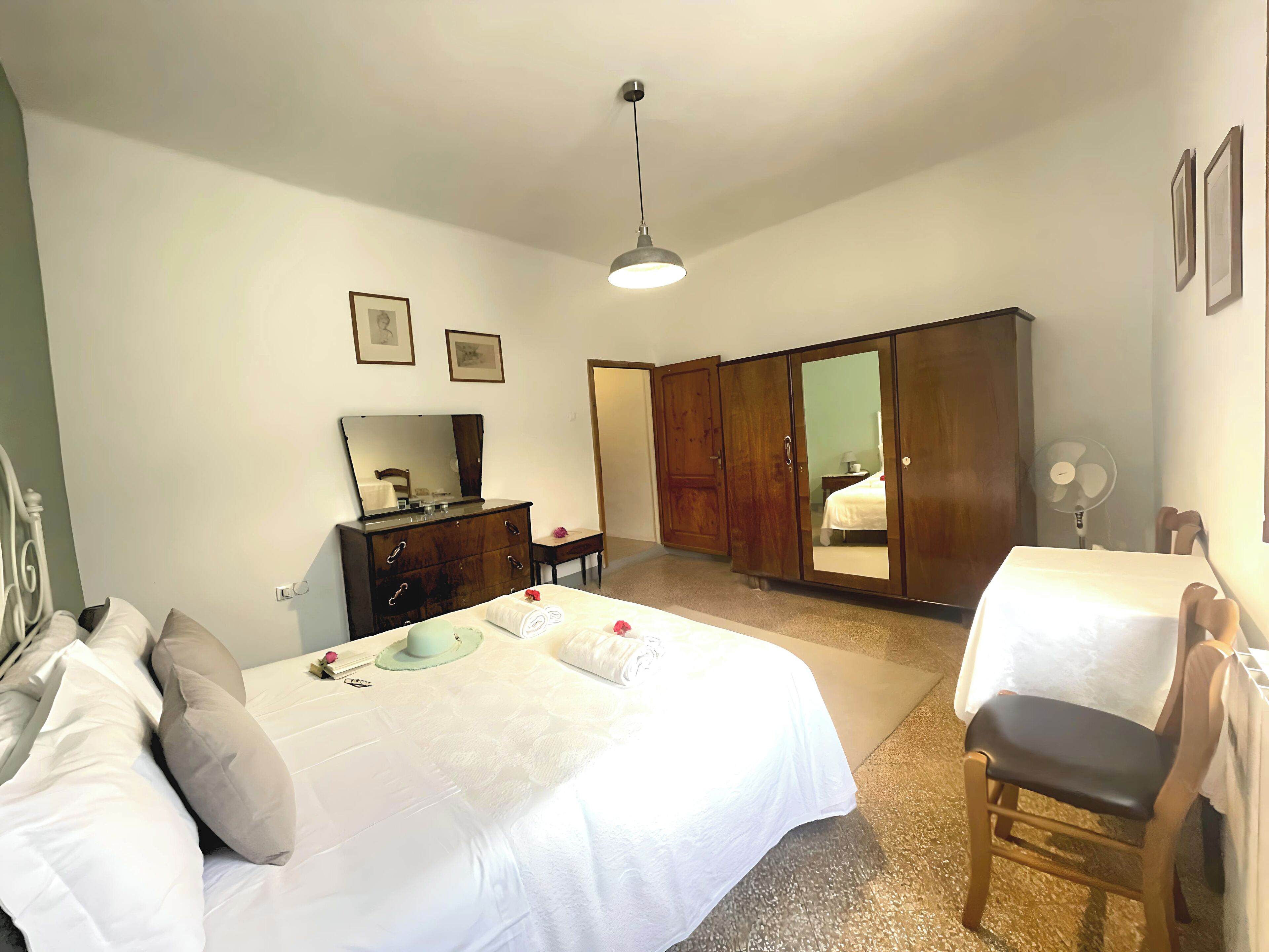 A bedroom with a bed, a dresser, a wardrobe, a chair, and a bedside table.